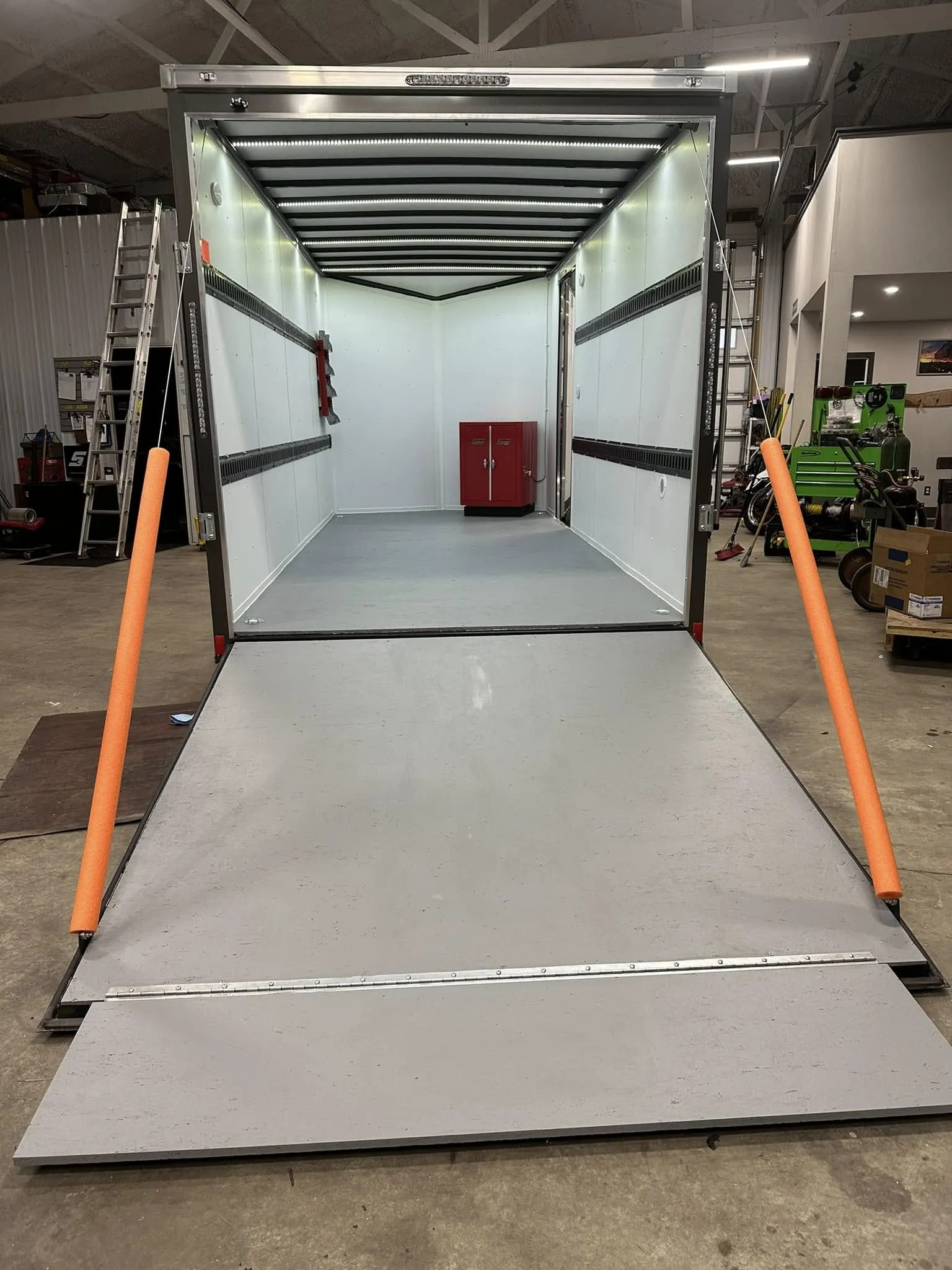 Lined white interior with E-track, a tool rack and cabinet, and a rear ramp door.