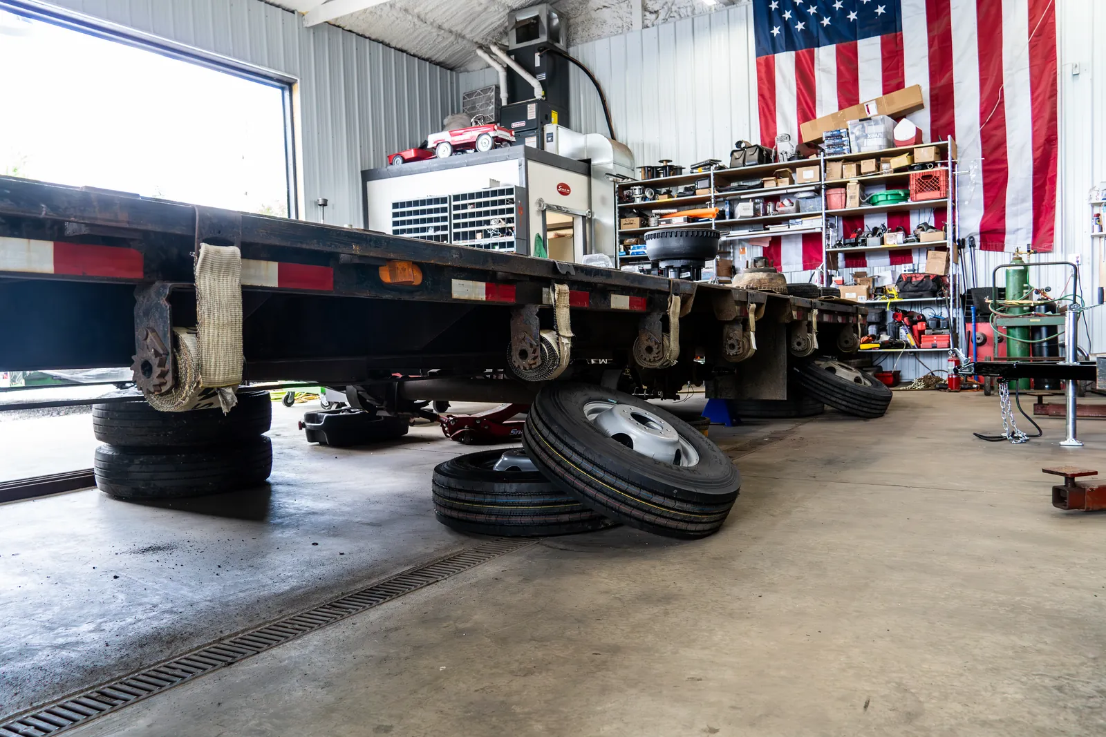 A flatbed trailer up on stands with the wheels off inside the Flatlander service shop